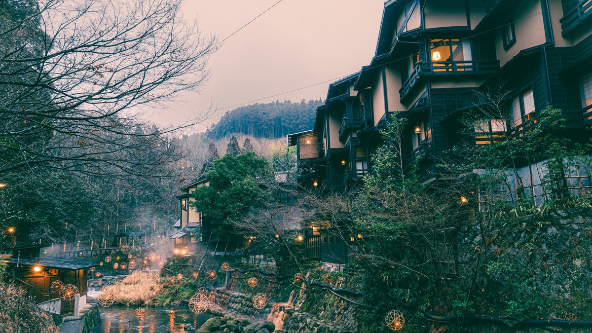 冬の夕暮れに灯りがともる温泉街の旅館（イメージ）
