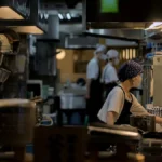 飲食店の厨房で調理にあたるスタッフ