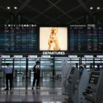 空港の出発フロア。「DEPARTURES」の案内表示と自動チェックイン機が並ぶ