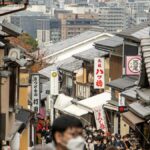 土産物店が並ぶ石畳の坂道を大勢の観光客が歩く