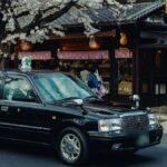 桜の咲く通りに停車した黒塗りのタクシー