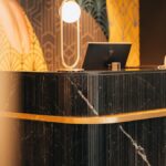 無人のホテルフロントカウンター。開いたノートパソコンとデスクランプが置かれている