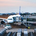 夕暮れの駐機場。ボーディングブリッジがついた旅客機と作業車両