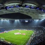照明に照らされた夜のサッカースタジアム。観客席が埋まっている
