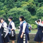 リュックを背負った制服姿の生徒たちが屋外を歩く