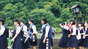 リュックを背負った制服姿の生徒たちが屋外を歩く