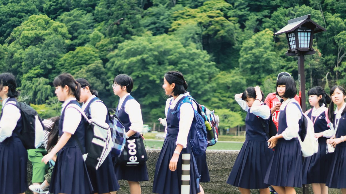 リュックを背負った制服姿の生徒たちが屋外を歩く