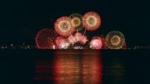 夜の湖上に打ち上がる大輪の花火と水面に映る光