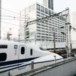 都市のビル群を背に高架を走る新幹線