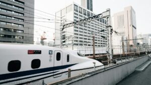 都市のビル群を背に高架を走る新幹線