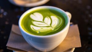 白い碗に注がれた抹茶ラテ。表面に葉の形のラテアートが描かれている