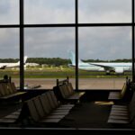 空港ターミナルの待合ロビー。窓の外に駐機中の旅客機が見える