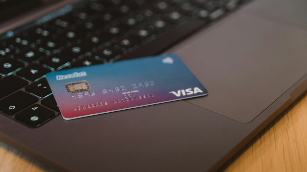 ノートPCのキーボードの上に置かれたクレジットカード。オンライン決済のイメージ