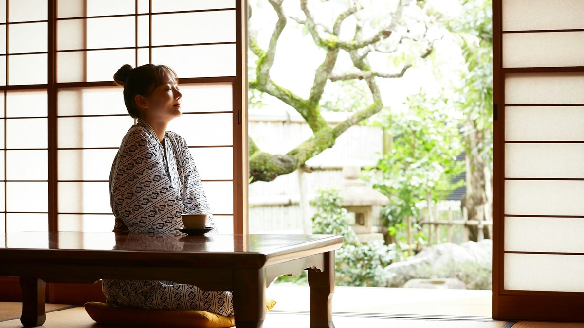 旅館の和室で庭を眺めながらくつろぐ浴衣姿の女性