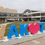 秋田駅前に置かれた「AKITA」の立体文字と秋田犬をかたどったオブジェ。奥にJR秋田駅
