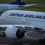 日本航空の旅客機が空港の誘導路をタキシングする様子。奥にはスカイマークのボーイング737が駐機している