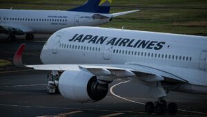 日本航空の旅客機が空港の誘導路をタキシングする様子。奥にはスカイマークのボーイング737が駐機している