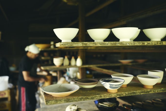 小石原焼の工房に並ぶ器と作陶する職人