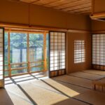 障子を開けた旅館の和室。庭の緑が見える窓から夏の日差しが差し込み、畳に格子状の影が伸びている