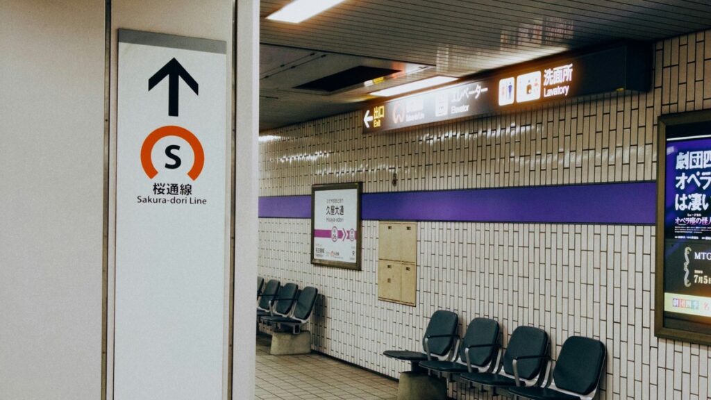 名古屋市営地下鉄・久屋大通駅のコンコース。左手に「桜通線」の案内サイン、正面の壁に駅名標「久屋大通」と名城線の紫帯、右手にベンチが並ぶ