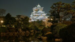 夜間にライトアップされた大阪城天守閣と、手前の日本庭園