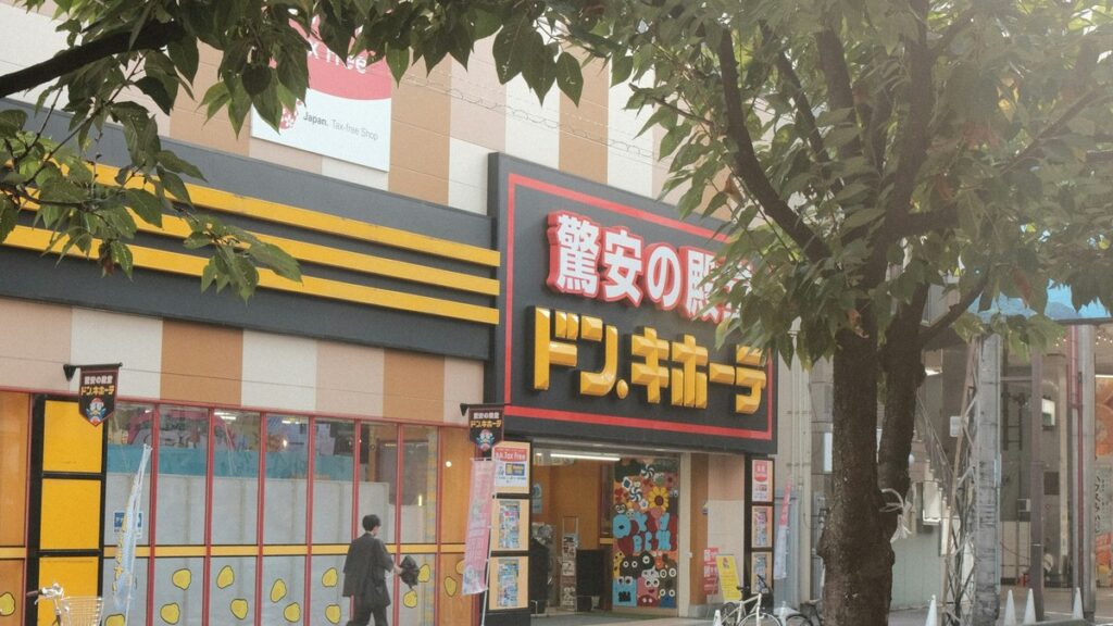 街路樹越しに見たドン・キホーテの店舗外観。入り口の脇に免税（Tax Free）の案内が出ている