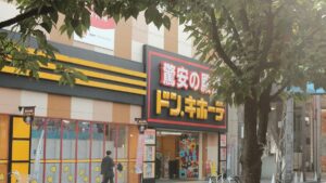 街路樹越しに見たドン・キホーテの店舗外観。入り口の脇に免税（Tax Free）の案内が出ている