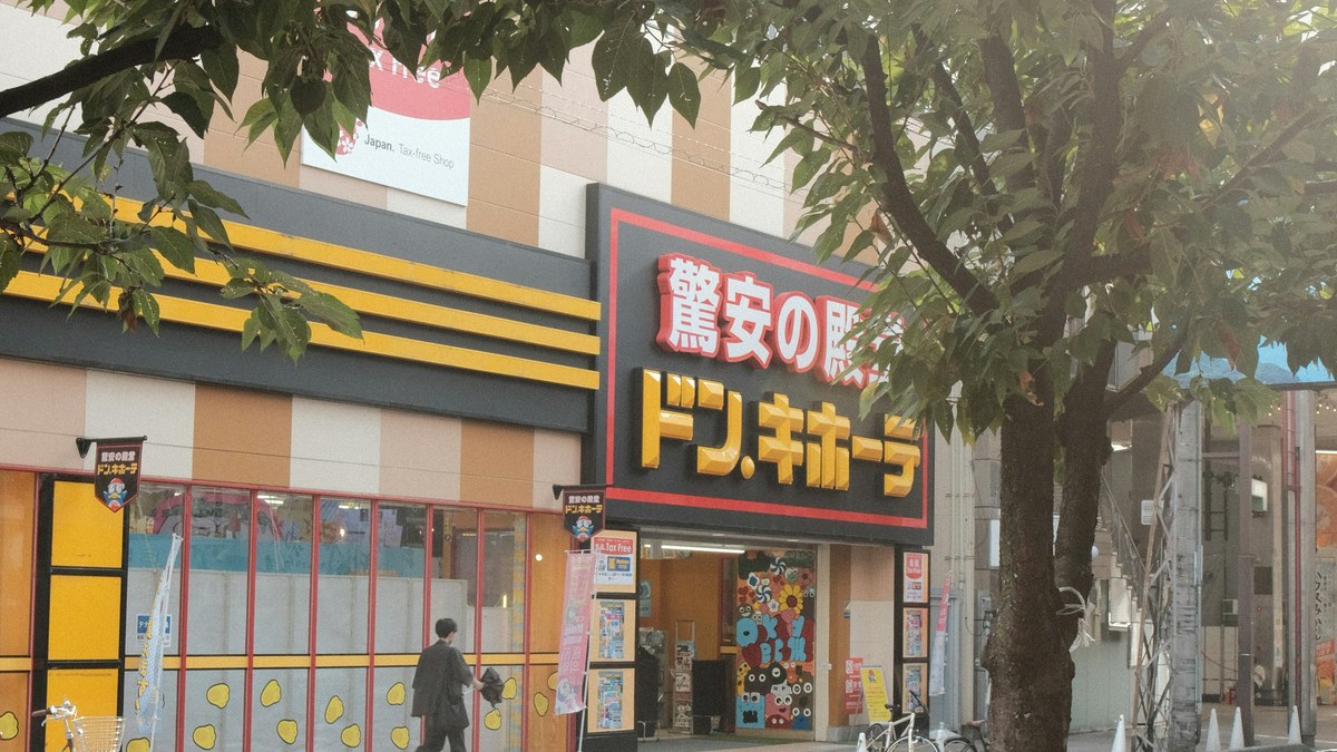 街路樹越しに見たドン・キホーテの店舗外観。入り口の脇に免税（Tax Free）の案内が出ている