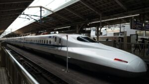 東京駅の東海道新幹線ホームに停車するN700系新幹線と、発車案内表示の下を行き交う乗客