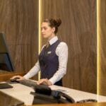 制服姿の受付スタッフがカウンターでパソコンを操作している様子