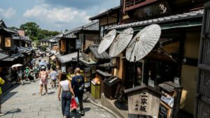 京都・二寧坂の石畳を歩く観光客。買物袋を提げた人もいる