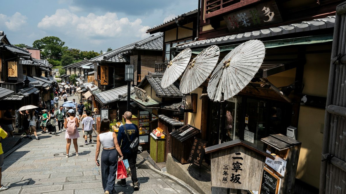 京都・二寧坂の石畳を歩く観光客。買物袋を提げた人もいる
