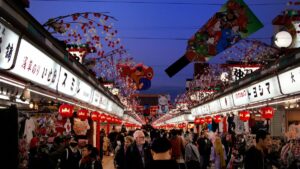 提灯と看板が並ぶ夕暮れの浅草・仲見世通りを行き交う買い物客