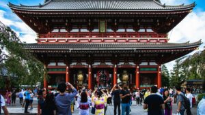 浅草寺の宝蔵門の前で、着物姿の人を含む大勢の観光客が写真を撮っている